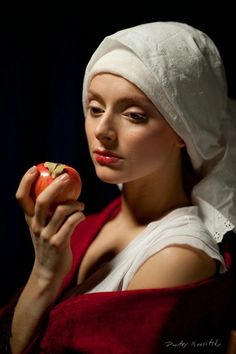 a woman wearing a white head scarf holding an apple