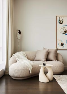 a living room filled with furniture next to a large white painting on the wall and wooden floor