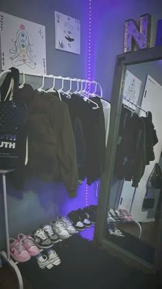 a closet with clothes and shoes hanging on the rack in front of a large mirror