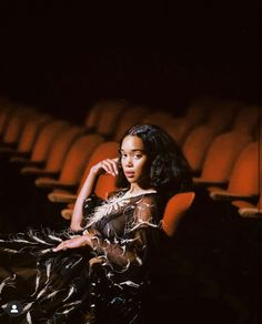 a woman is sitting in an empty theater with her hand on her hip and looking off to the side