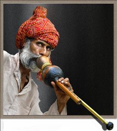 an old man with a red turban holding a wooden stick