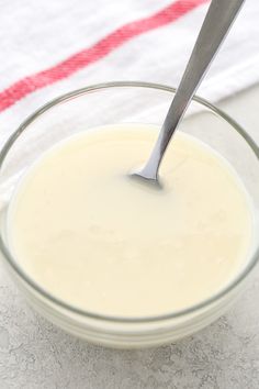 a glass bowl filled with white liquid and a spoon in the middle, on top of a towel