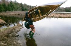 a man carrying a kayak across a body of water