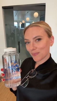 a woman is holding a water bottle and glasses