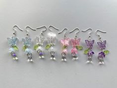 six pairs of dangling earrings with butterfly charms on them, all in different colors and sizes