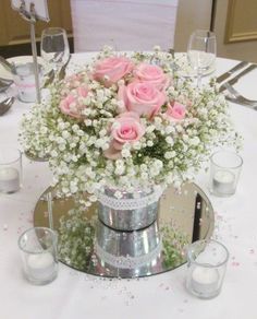 pink roses and baby's breath in a silver vase on a white table cloth