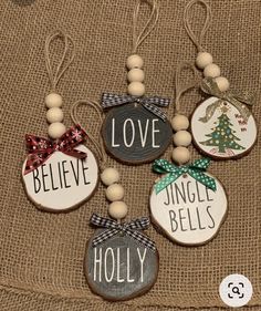 christmas ornaments with words and bows are hanging on a burlap cloth covered surface