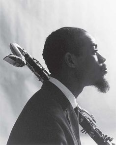 a black and white photo of a man in a suit with a saxophone on his shoulder