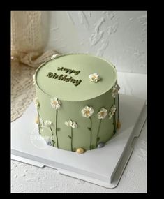 a green birthday cake with white flowers on it