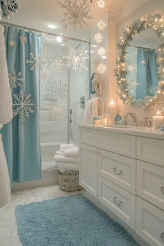 a bathroom decorated in blue and white with snowflakes on the shower curtain, rugs and lights