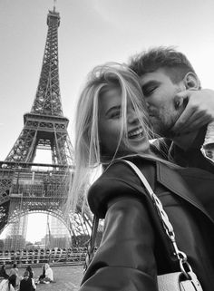 a man and woman standing next to each other in front of the eiffel tower