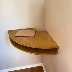 a laptop computer sitting on top of a wooden shelf next to a white painted wall