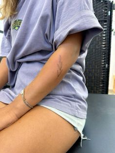 a woman sitting on top of a table with her legs crossed and tattoos on her arm