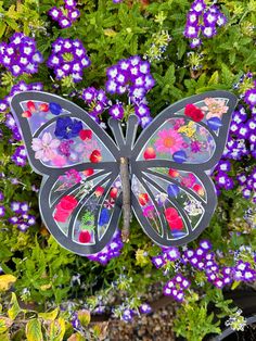 a metal butterfly sitting on top of purple flowers