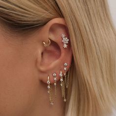 a woman wearing three different ear piercings on her left ear and the other two are gold