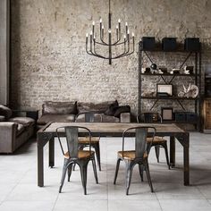 an industrial style dining table and chairs in front of a brick wall with exposed lighting