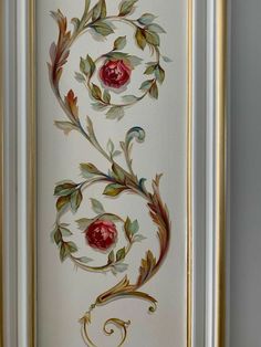 an ornate painting on the side of a wall with gold trimmings and red flowers