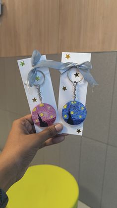 someone is holding up two key chains that are shaped like trees with stars on them