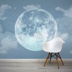 a white chair sitting in front of a wall with a large moon on it's side