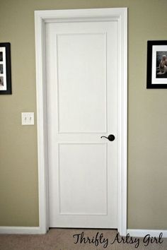 a white door in a room with pictures on the wall and carpeting around it