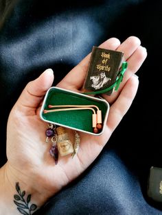 a person holding a small book and some other items in their hands with a tattoo on her arm