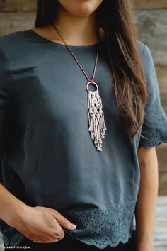 a woman wearing a necklace with beads on it and a black shirt is standing in front of a wooden wall