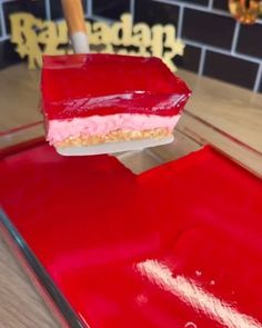 a person holding a spatula over a red cake