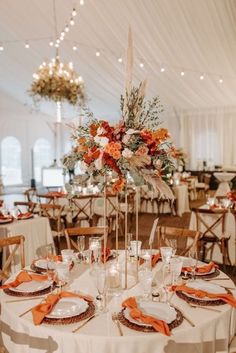 an image of a table setting at a wedding reception with orange and white flowers on the centerpieces