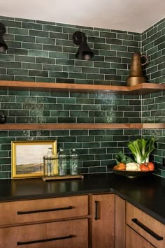 a kitchen with green tiled walls and wooden cabinetry, black counter tops and wood cabinets