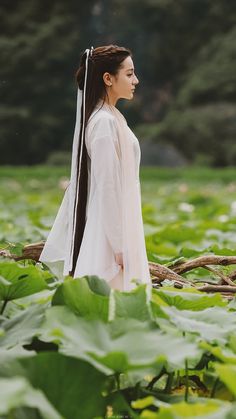 a woman with long hair wearing a white dress and holding a stick in her hand