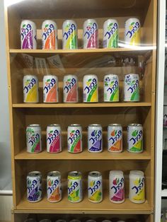 a display case filled with lots of different types of sodas on wooden shelving