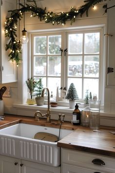 a kitchen decorated for christmas with wreaths and garland on the window sill above the sink