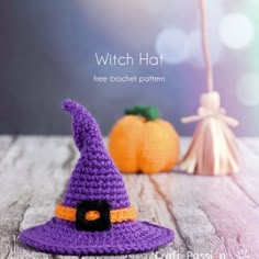 a crocheted witch hat sitting on top of a wooden table next to two pumpkins