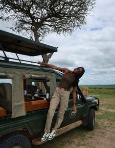 a man standing on the back of a green truck in front of a large tree