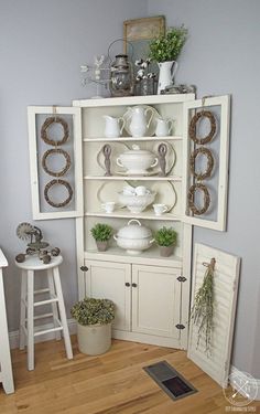 a white china cabinet filled with dishes and flowers