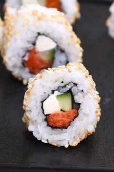 sushi rolls with cucumber, avocado and sesame seeds on a black tray