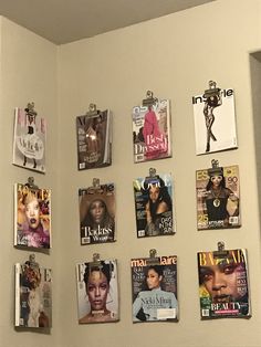 several magazine covers hang on the wall next to a toilet in a room with white walls