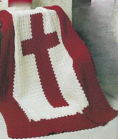 a red and white crocheted blanket sitting on top of a table next to a chair