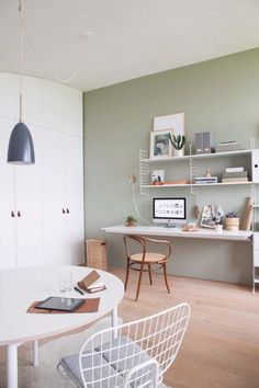 a white table and chairs in a room with shelves on the wall behind it,