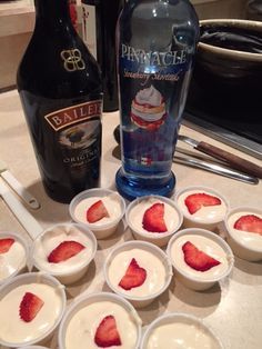 small bowls filled with strawberries next to a bottle