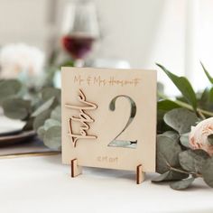 a wooden table number sitting on top of a table next to a vase with flowers