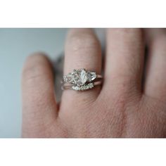 a woman's hand with a diamond ring on top of her finger and the other hand holding an engagement ring