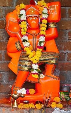 an orange statue sitting on top of a brick wall next to flowers and other items