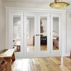 an empty room with white doors and wood flooring on the wooden floor next to a bench