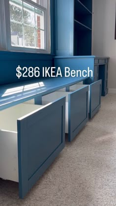 a kitchen with blue cabinets and white counter tops on carpeted floor next to window