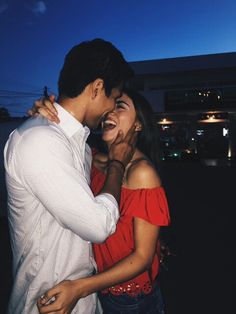 a man and woman standing next to each other in front of a building at night