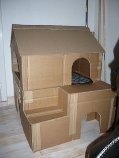 a dog house made out of cardboard with a cat bed in the top and bottom