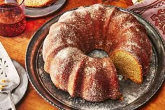 a bundt cake with powdered sugar on top sits on a metal platter