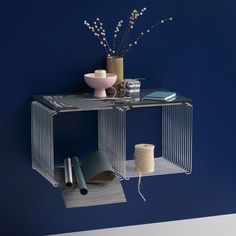 a metal shelf with various items on it in front of a blue wall and white floor