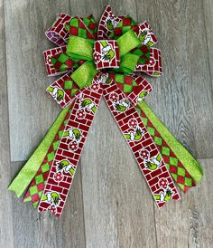 a green and red bow with peanuts on it sitting on top of a wooden floor